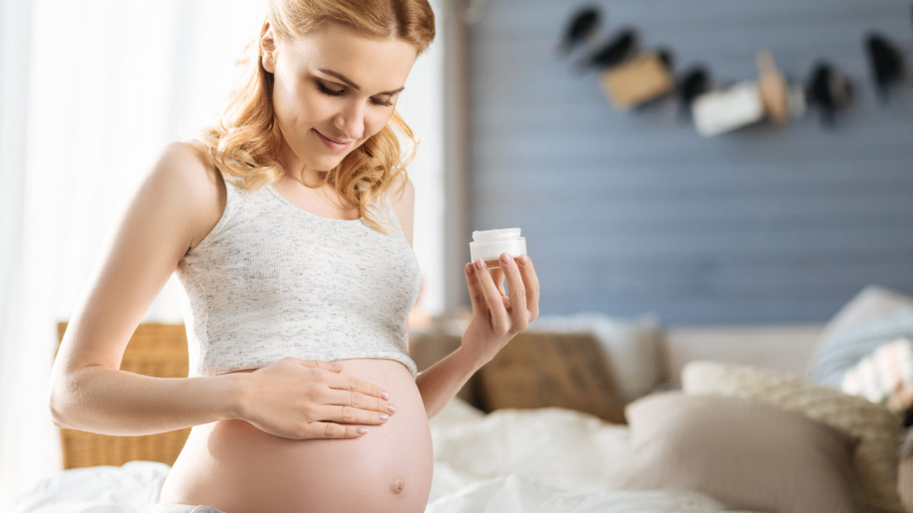 Pregnant woman gently rubbing the cream in her belly